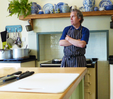 John Ramsay chef by the Aga in typical country house kitchen